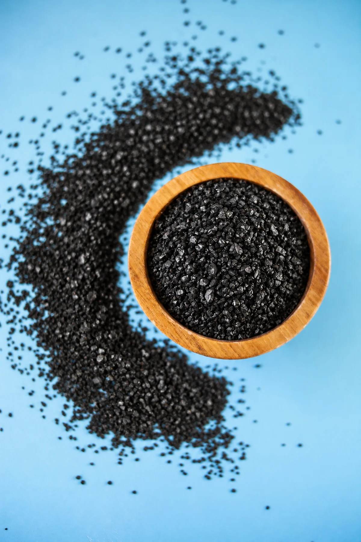 Carbone attivo granulare Watercel Carbon in una ciotola su sfondo blu.